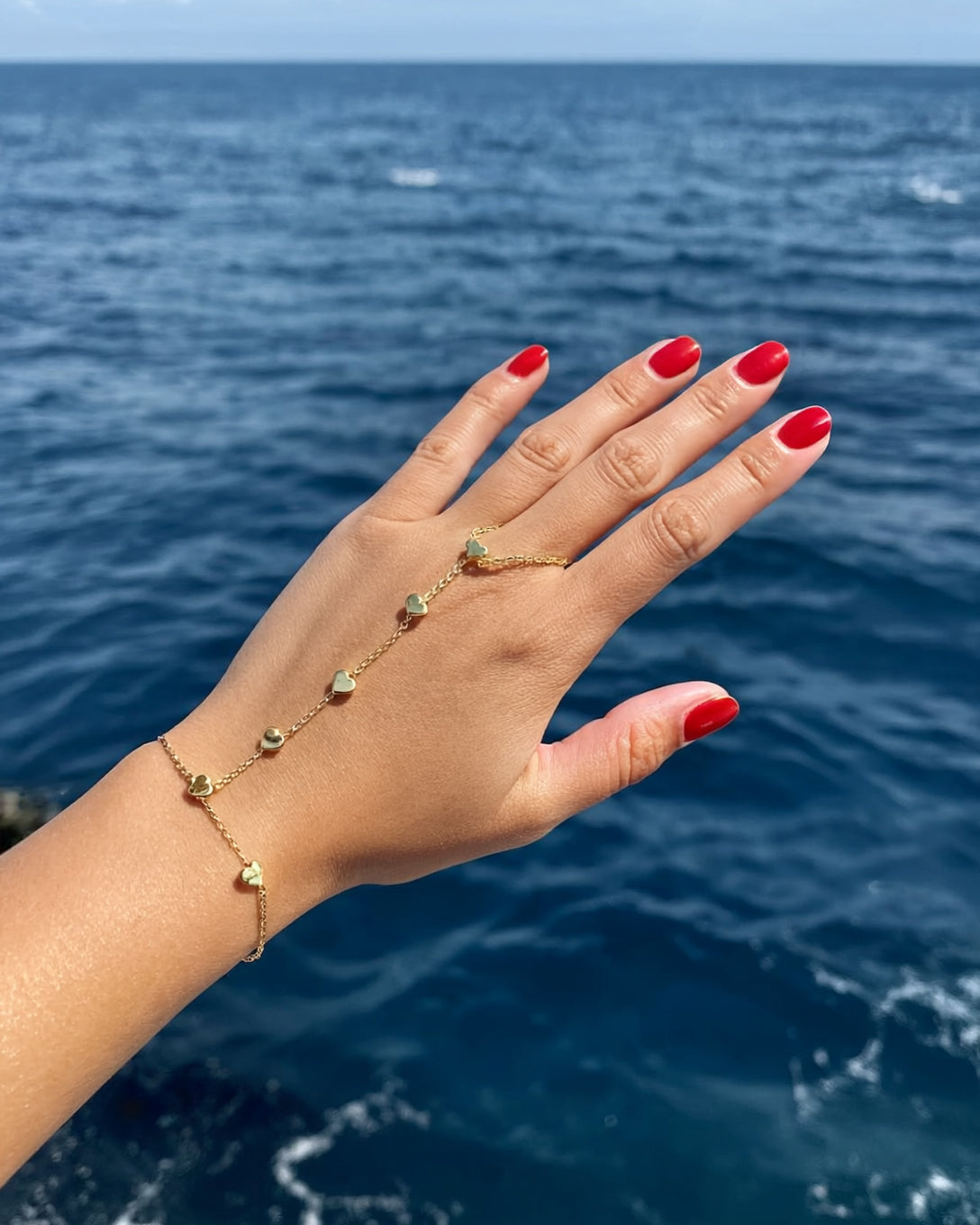 Gen4-pulseraanillo-dorada-con-corazones-esta-puesta-en-una-mano-de-mujer-con-unas-rojas_-e-118329581.jpg